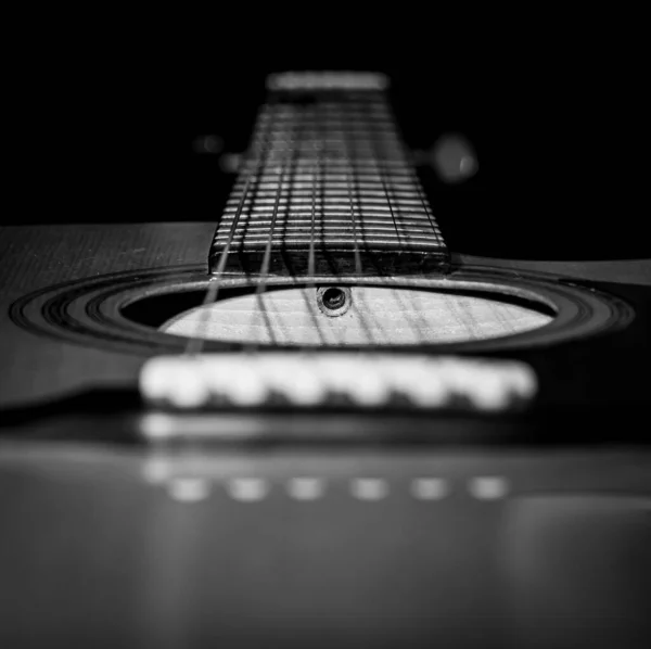 Siyah arkaplanlı akustik gitar yakın çekim görüntüsü. Seçici odaklanma. B & W.