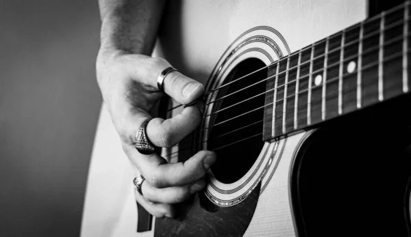 Klasik yüzükler çalan ve akustik gitar çalan bir el. Yakın çekim görüntüsü. Seçici odaklanma. Tahıl. B & W.