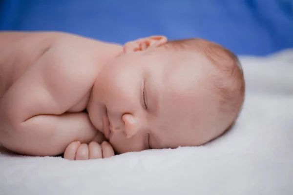 Tatlı uyuyan yeni doğmuş bebek beyaz yatak örtüsünde