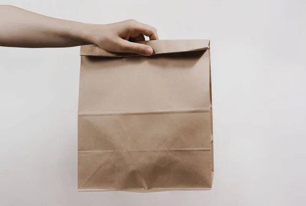 Kadın, beyaz arka planda açık kahverengi boş el işi kağıt torbasını tutuyor. Paketleme şablonu modeli. Uzayı kopyala Reklam alanı. Teslimat hizmeti kavramı. 