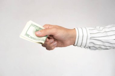Gri bir arka planda parası olan bir el. Ödeme, para değişimi, rüşvet kavramı..