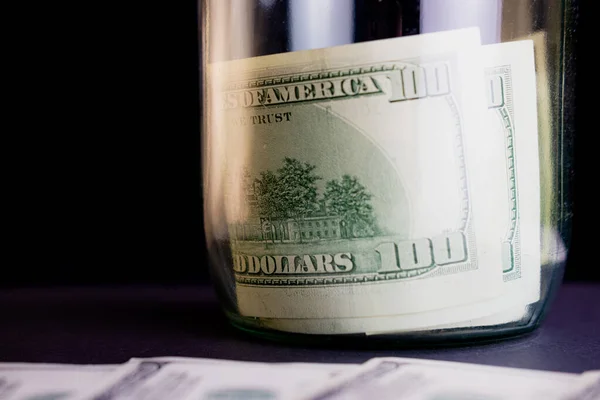 Siyah arka planda cam bir kavanozda dolar banknotları. Kavanozda para tasarrufu