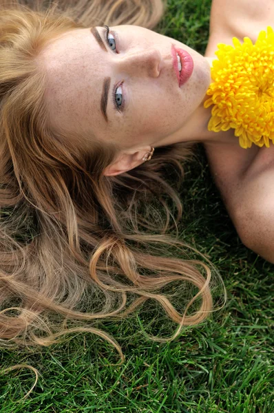 Chica acostada en la hierba con flores amarillas . — Foto de Stock