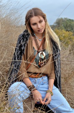 Açık havada kuru otların arasında oturan sarışın