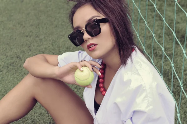 Модель с теннисным мячом сидит рядом с сеткой . — стоковое фото