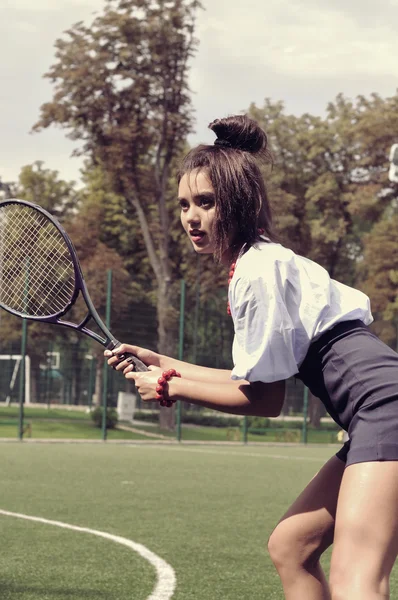Dívka hraje tenis na zelený dvůr — Stock fotografie