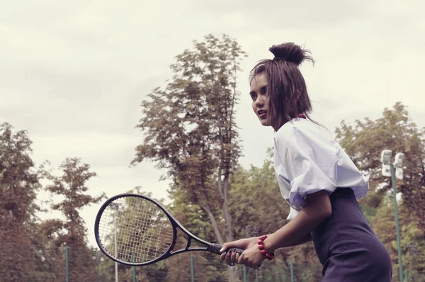 Dívka hraje tenis na zelený dvůr — Stock fotografie