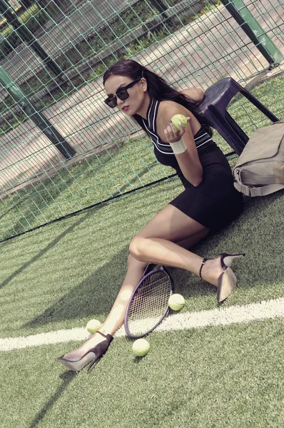 Chica se sienta en la hierba en la cancha de tenis — Foto de Stock