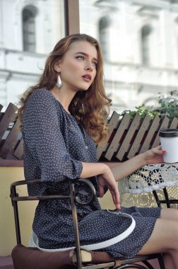 Kadın açık bir kafede kahve içiyor