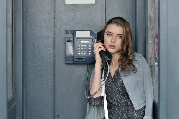 Girl holding a payphone handset in her hand — Stock Photo, Image