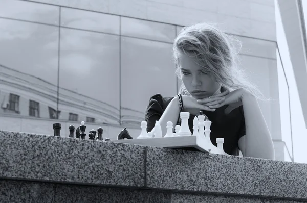 Портрет девушки, которая смотрит на шахматную доску — стоковое фото