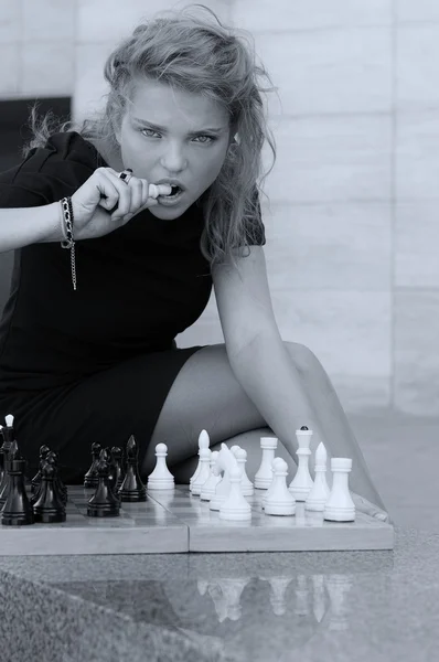 Девушка пытается откусить от шахматной королевы — стоковое фото