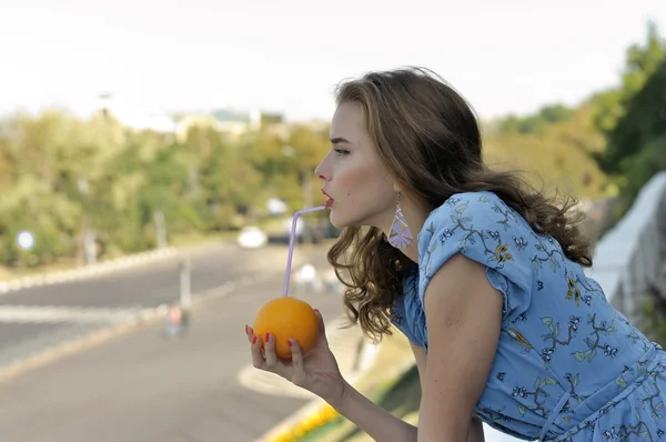 Krásná dívka je pití šťávy brčkem z oranžové Royalty Free Stock Fotografie