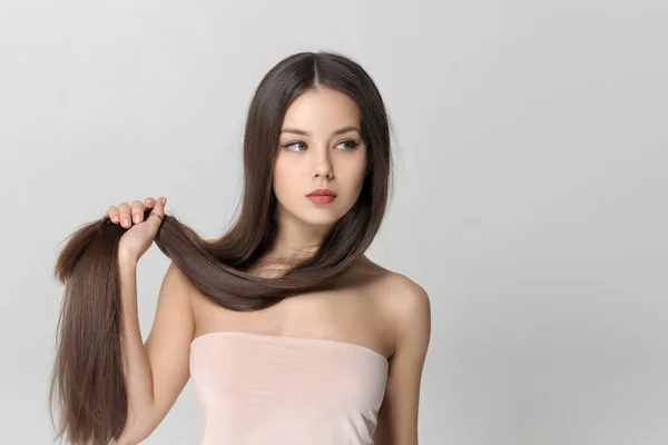 Girl holds her long hair on her arm — Stock Photo, Image