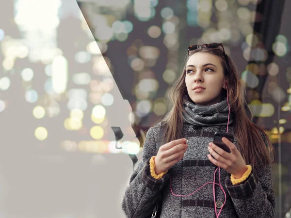 Chica camina por la calle de la ciudad sosteniendo un teléfono inteligente —  Fotos de Stock