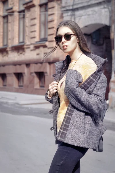 Девушка в сером пальто переходит дорогу — стоковое фото