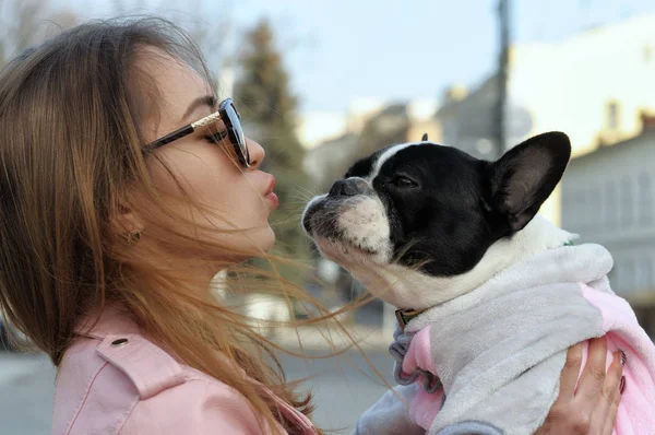 Girl kisses her pet while holding him in her arms