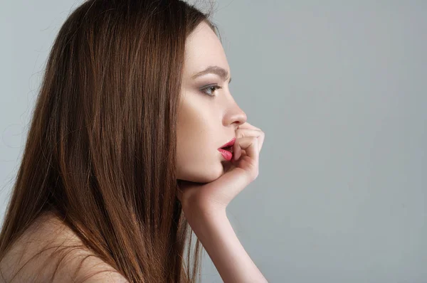 Girl sits in profile leaning her head on her arm — Stock Photo, Image