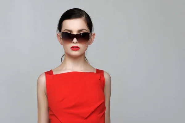 Bella ragazza con trucco serale in abito rosso e occhiali da sole — Foto Stock