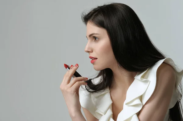 Portrait en profil d'une jolie fille qui tient un rouge à lèvres l — Photo