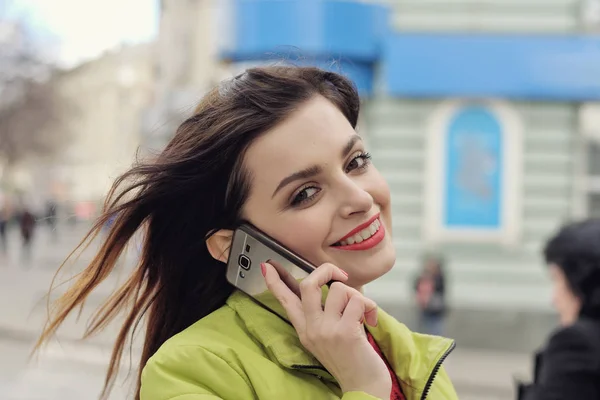 Menina está falando ao telefone enquanto caminha pela cidade — Fotografia de Stock