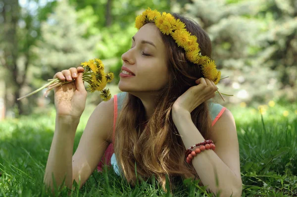 Ele menina encontra-se na grama com uma coroa de flores silvestres em seu h — Fotografia de Stock