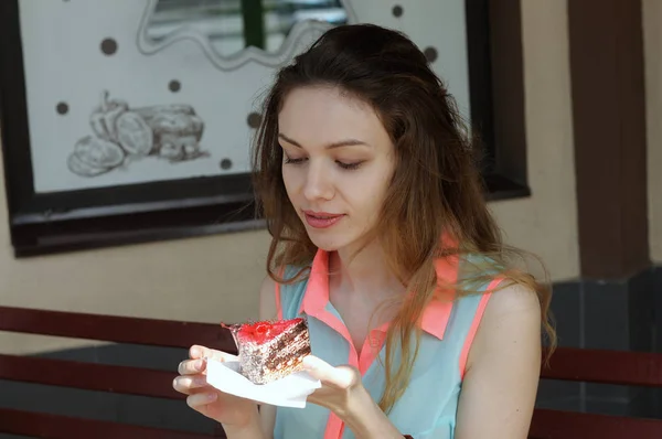 Το κορίτσι τρώει ένα κέικ σε μια υπαίθρια καφετέρια — Φωτογραφία Αρχείου