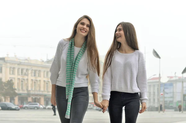 Zwei Freundinnen gehen durch die Stadt, halten Händchen und — Stockfoto