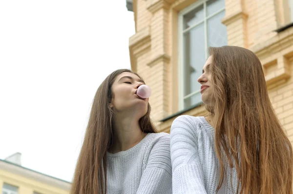 Zwei Mädchen ruhen sich aus und blasen Kaugummiblasen auf — Stockfoto