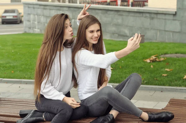 Две девушки делают селфи фото и показывают рога — стоковое фото