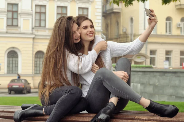 Две девушки обнимаются и смеются, делая селфи-фото. — стоковое фото