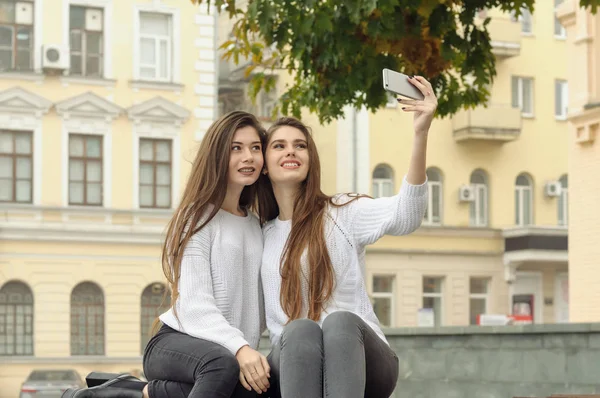 两个女朋友靠在一起当他们做一个 selfi — 图库照片