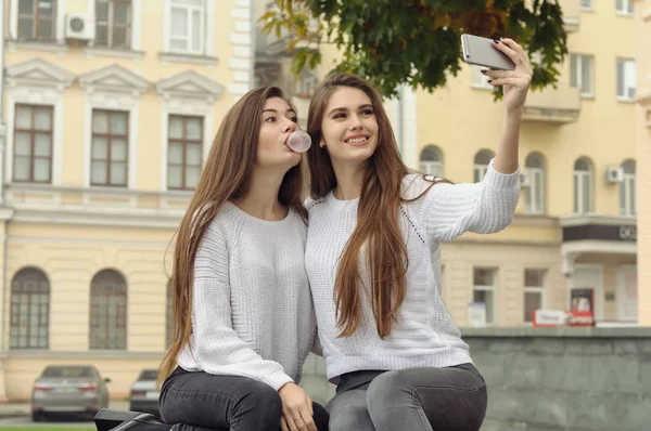 Zwei Freundinnen pusten Blasen aus Kaugummi, während sie machen — Stockfoto