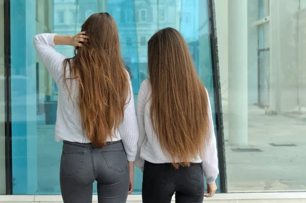 Zwei Mädchen mit schlanker Figur stehen mit dem Rücken zur Wand Stockfoto