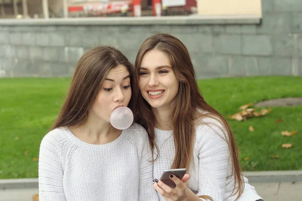 Twee brunettes kijken naar foto's op hun smartphone — Stockfoto