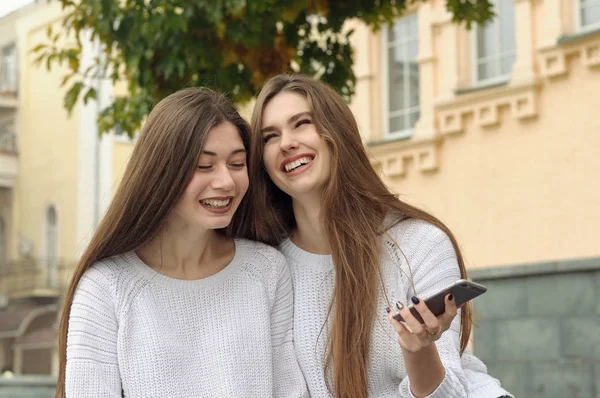 两个女孩聊天时笑得很开心, 挥舞着智能手机 — 图库照片