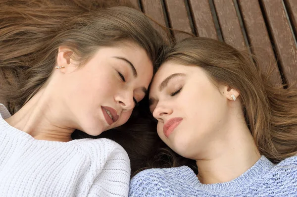 Dois amigos se deitam em um banco encostando a cabeça uns contra os outros — Fotografia de Stock