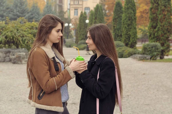 Two girlfriends try to warm up with a hot drink in the outdoors — Stock Photo, Image