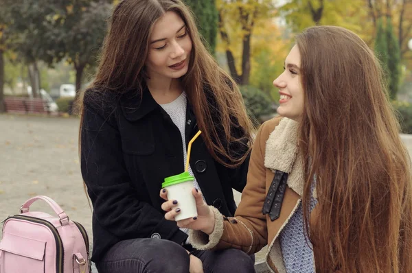 Zwei Freundinnen versuchen sich mit einem heißen Getränk im Freien aufzuwärmen — Stockfoto