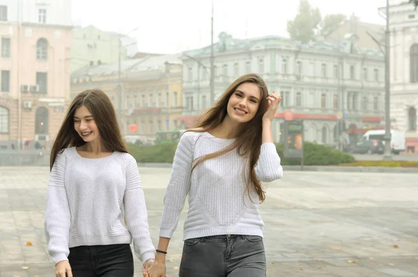 Zwei Freundinnen laufen Händchen haltend über den Platz — Stockfoto