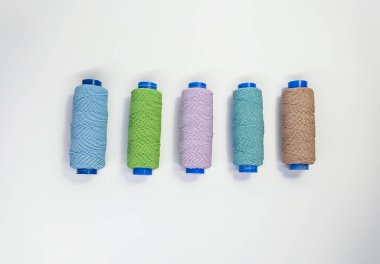 Beyaz arkaplanda pastel renklerde renkli dikiş iplikleri, üst görünüm