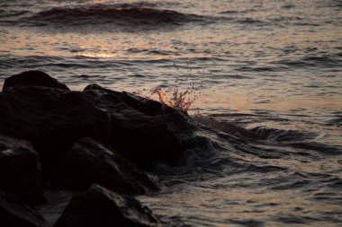 Şafak vakti deniz dalgaları taşlara çarpar