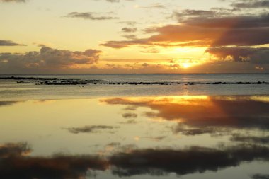 Sahilde gün batımı ve sonsuz bir havuzun suyundaki yansıma.