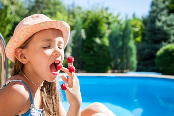 Young girl eating raspberries from her fingers Royalty Free Stock Images