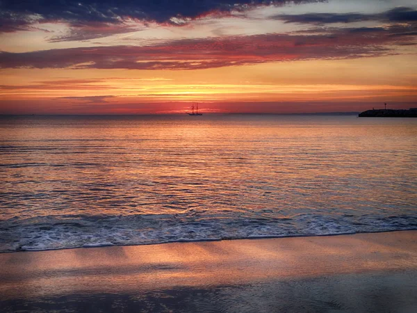 Ιστιοφόρο στο πολύχρωμο Ανατολή του ηλίου από την παραλία — Φωτογραφία Αρχείου