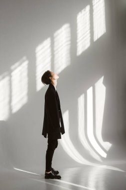 Beyaz arka planda, güneş altında ceketli bir kız.