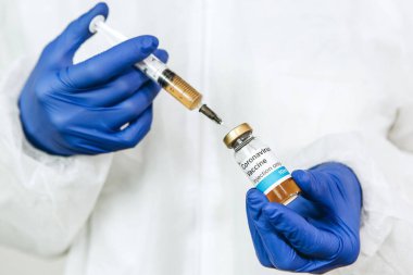 Bir tıp laboratuarı çalışanı şırıngada aşı buldu. Covid-2019 'dan karteller. 2020 salgını. Mavi eldivenli bir doktor şırıngada ilaç buldu. Aşıyı test etmek.