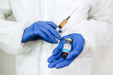Beyaz cüppeli ve mavi eldivenli bir doktor, içinde koronavirüs aşısı olan bir şırınga tutuyor. Covid-2019 'dan aşı enjekte edildi. Pandemik koronavirüs 2020. Aşı testi.