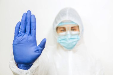 Tıbbi maskeli bir doktor, takım elbiseli bir günahkar ve beyaz bir arka planda mavi eldivenler. Salgın covid-2019 'u durduralım. Yakın plan bir doktorun portresi..