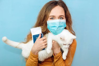 Genç bir kız kollarında beyaz bir kedi tutuyor. Mavi arka planda kıvırcık saçlı sarışın bir kızın portresi. Hayvan koruma kavramı. Sığınaktan kediyi al..